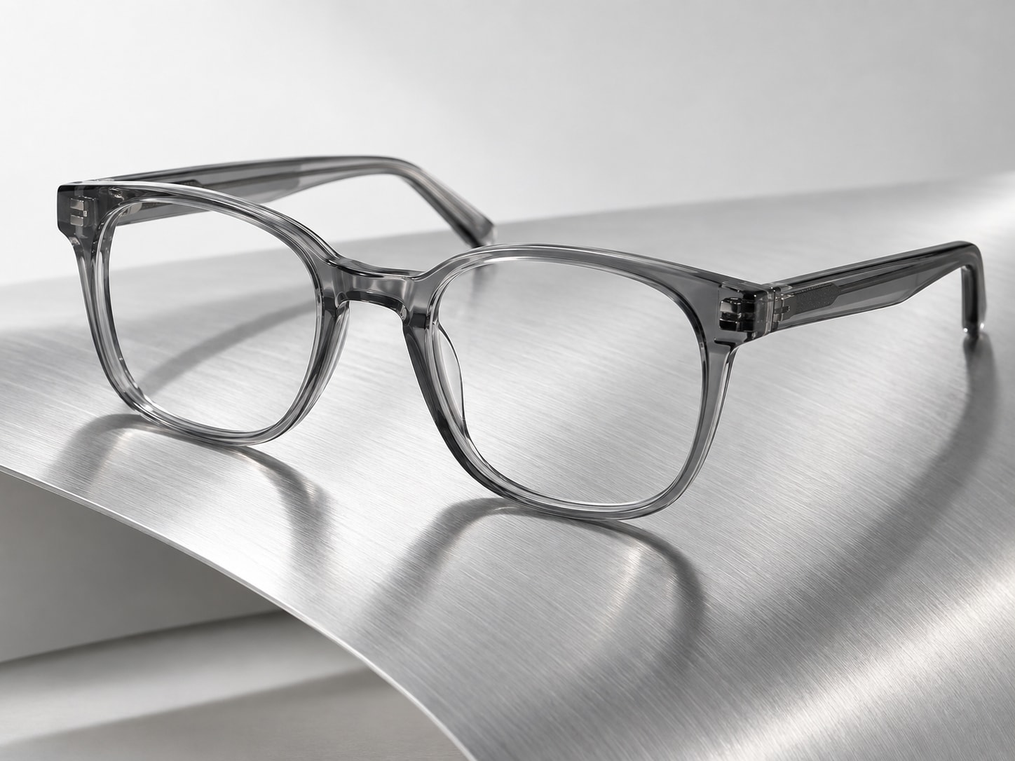 Armação translúcida com lentes transparentes sobre uma superfície curva de alumínio